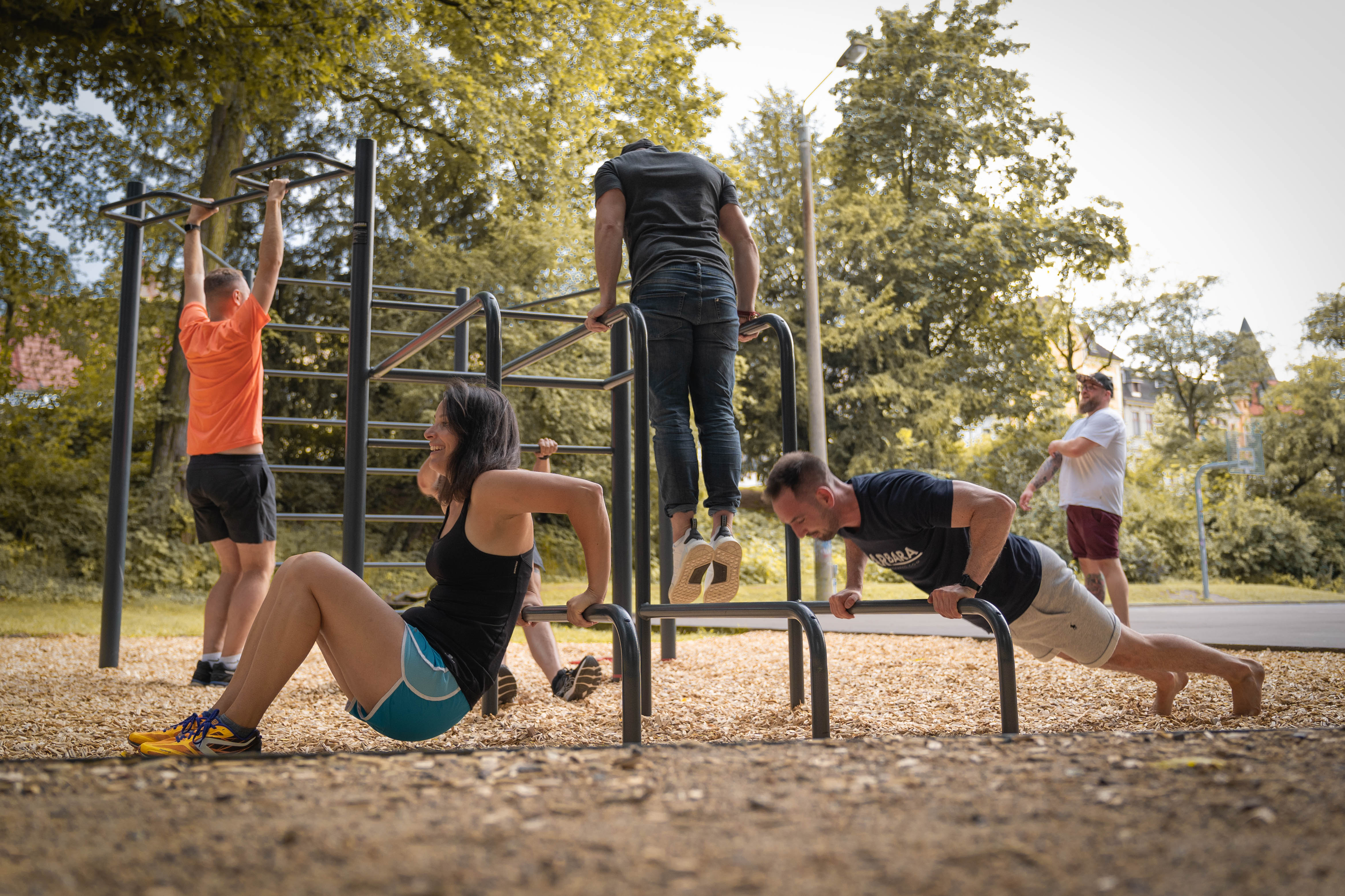 Group training at an outdoor fitness park with pull-up bars and dip stations